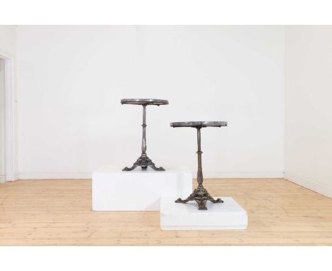 A pair of marble and polished cast iron bistro tables, early 20th century, French, each raised on a fluted column and acanthu
