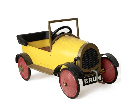 A vintage "Ragdoll Brum 2003" ride-on pedal car in yellow and red with pedals and crank handle, the number plate inscribed "B