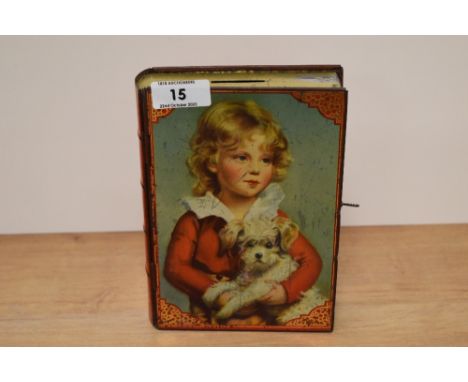 A vintage tin money box in the form of a book with depiction of child and dog to front, with key.