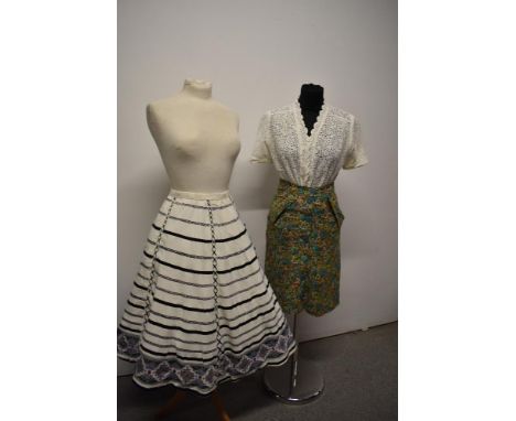 A 1950s fairly full cotton skirt, having pink, blue, grey and black patterns to white ground with side metal zip, medium size