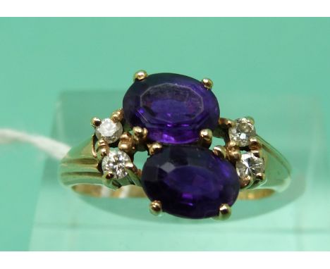 A 9ct gold ring set with two oval mixed cut amethysts and diamonds (size M)