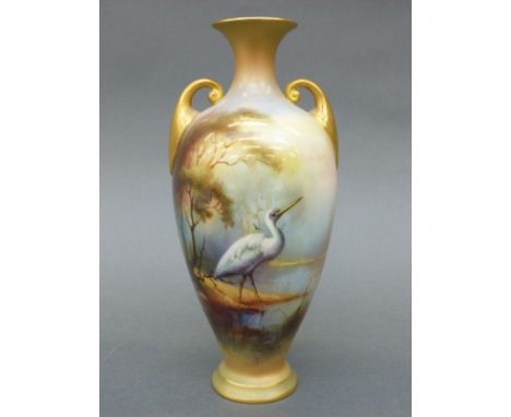 Royal Worcester twin handled pedestal vase decorated with a stork or crane in a continuous  landscape, monogrammed by James H