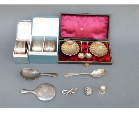 Three boxed hallmarked silver napkin rings, a silver caddy spoon, a miniature silver-mounted hand mirror, a teaspoon and a pa