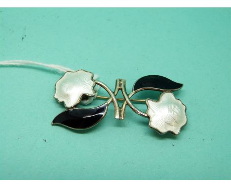 A silver brooch set with black and white enamel in a foliate design 