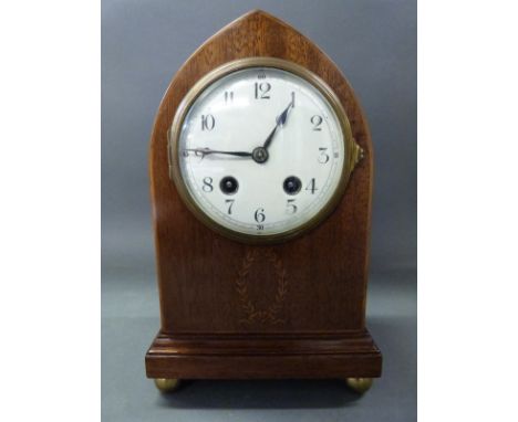 An Edwardian inlaid mahogany mitre shaped mantel clock with laurel leaf inlaid decoration, the silvered Arabic dial with blue