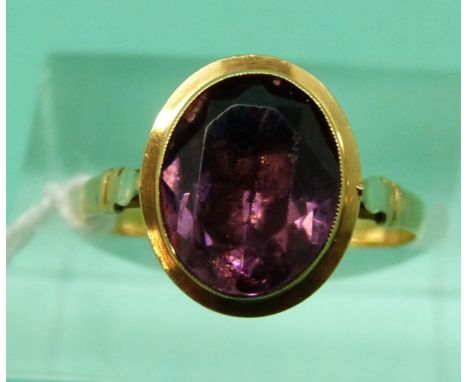 A yellow metal ring set with an oval amethyst in a foiled setting (Size N)
