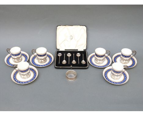 A set of six hallmarked silver-mounted Royal Worcester coffee cups and saucers, a crested set of hallmarked silver spoons and