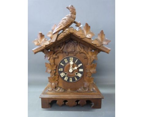 An early 20thC Black Forest two train mantel cuckoo clock striking on a gong with vine leaf and cuckoo carving to case, Roman