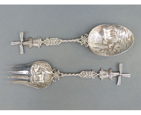 A pair of Dutch white metal fork and spoon salad servers, with embossed bowls and windmill finials, one with Dutch silver mar