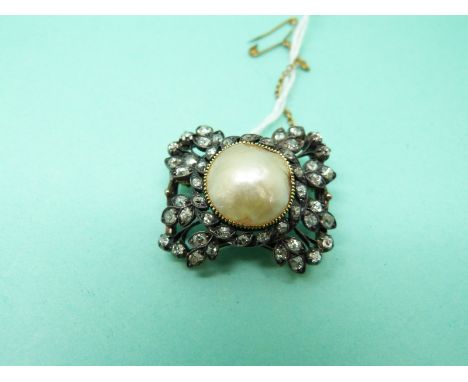 An early Victorian brooch set with a pearl cabochon to the centre surrounded by old mine cut diamonds in a stylized bow desig