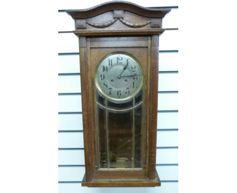 An oak-cased c1910 wall clock in lightly carved case with, bevelled glass door, the silvered Arabic dial with blued spade han