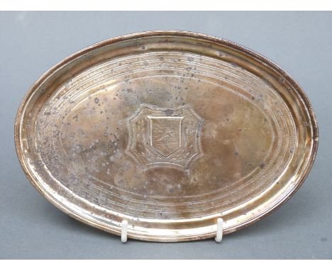 A George III hallmarked silver card tray or teapot stand of oval form, with engine turned decoration and heraldic crest, Lond