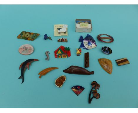 A collection of largely treen and ceramic brooches to include dolphin, sheep, fish, cottages together with enamel examples