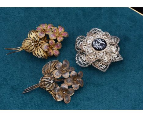 Three filigree brooches, two of floral design and one circular flower head centred with an enamel exotic bird, 26.9g