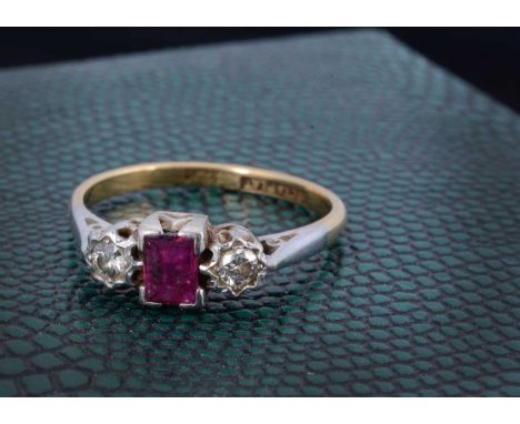An 18ct gold and platinum three stone dress ring, the rectangular cut ruby flanked by illusion set diamonds, ring size O, 3.2