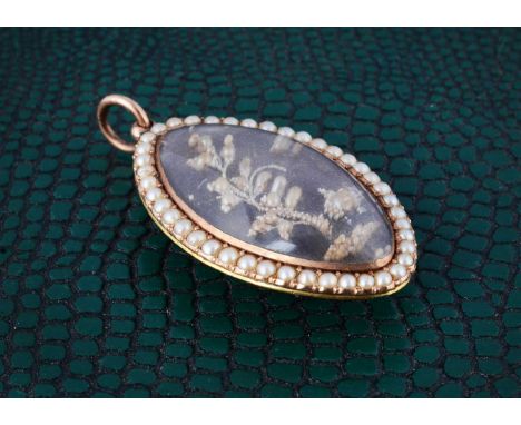 An 18th Century navette shaped seed pearl and white enamel mourning pendant, with plaited panel the reverse with seed pearl a