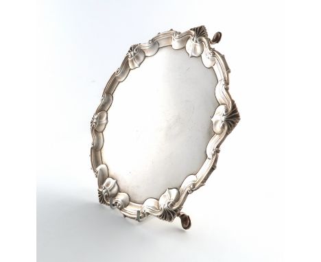 A silver salver, by William Hutton and Sons, Sheffield 1917, circular form, shell and scroll border, on three hoof feet, diam