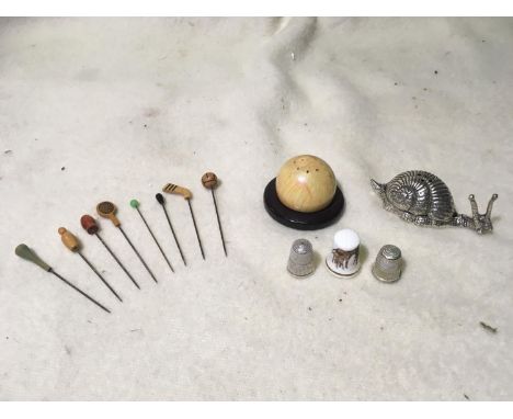 A prickly lot: 6 hat pins; wooden ball with stick pins; pewter snail with 6 stick pins, 5 thimbles and one china thimble 