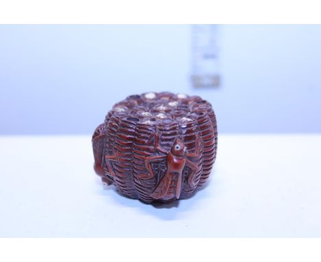 A Japanese hardwood netsuke in the form of a beehive signed to the base 