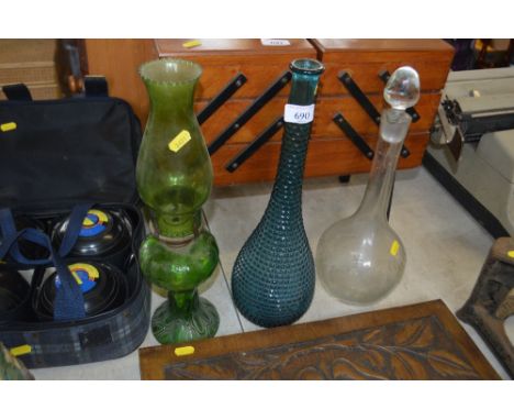 A blue glass bottle; a green glass oil lamp; and a decanter and stopper 