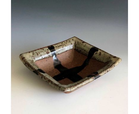A Janet Leach square dish with ash glazed rim and tenmoku cross, width 15cm, height 4.5cm.