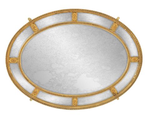 A 19TH CENTURY ADAM STYLE GILT OVAL HANGING MIRROR the bead-edged panelled border set with oval flower head medallions enclos