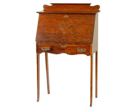 AN ART NOVEAU OAK BUREAU with leaf carved angled fall revealing a fitted interior of pigeon holes, shaped frieze drawer raise