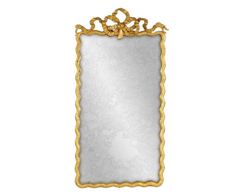 AN 18TH CENTURY CARVED GILT WOOD HANGING MIRROR with ribbon work pediment and slender waved edge surround141cm high 76cm wide