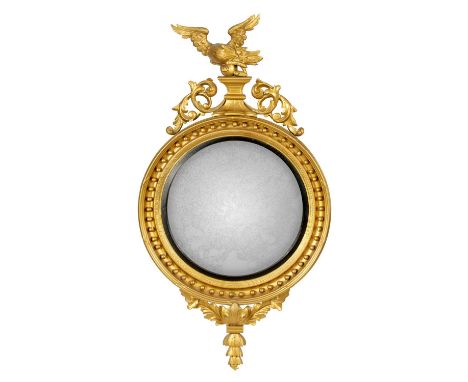 A LARGE REGENCY CARVED GILT WOOD CONVEX HANGING MIRROR with eagle surmount above a leaf carved pediment; with moulded frame a