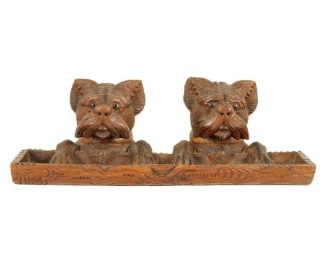 A 19TH CENTURY BLACK FOREST CARVED DOUBLE INK STAND AND PEN TRAY realistically modelled as the heads and paws of two dogs ove