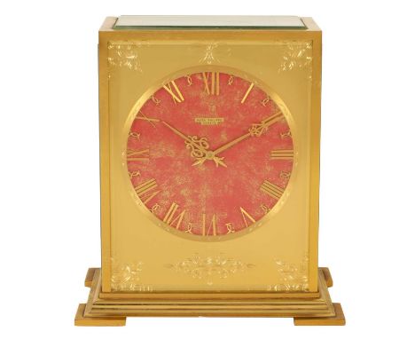 PATEK PHILLIPE. A MID 20TH CENTURY GILT BRASS SOLAR POWERED TABLE CLOCK the burgundy and gold coloured dial with roman chapte