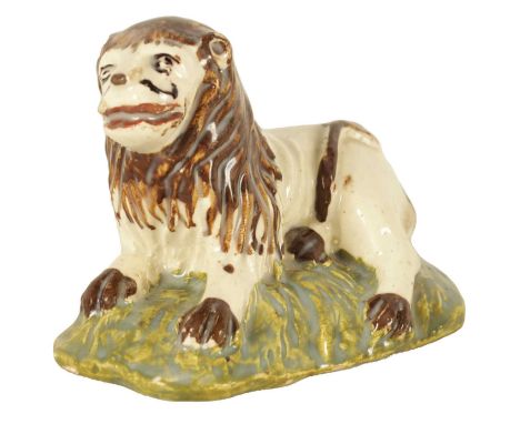 AN EARLY 19TH CENTURY STAFFORDSHIRE SCULPTURE OF A RECUMBENT LION decorated in polychrome colours11cm wide 8cm highIt is in u