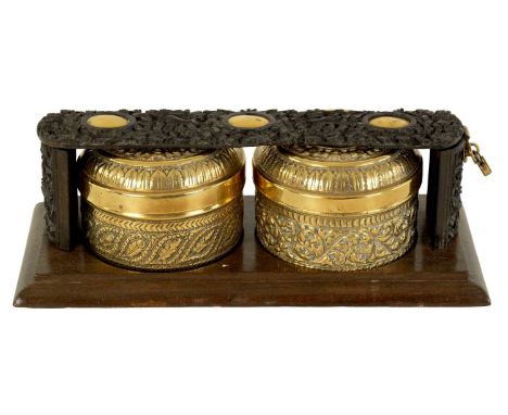A 19TH CENTURY CHINESE CARVED HARDWOOD AND BRASS TEA CADDY with two lidded embossed brass tea canisters, locked by a leaf car
