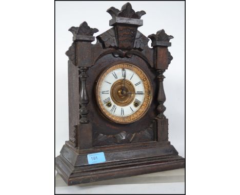 An early 20th century eight day movement gothic style carved oak mantle clock, having an enamel face with a roman numeral cha