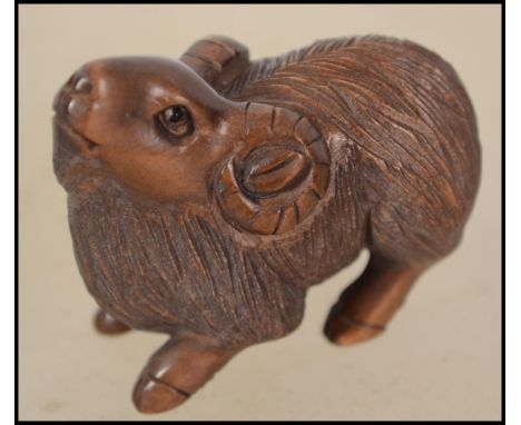 A Japanese carved netsuke in the form of a goat signed to the underside
