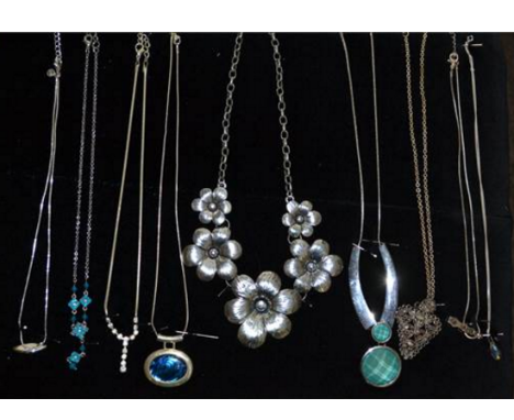 A group of costume jewellery and silver necklaces mounted on a velvet cushion.