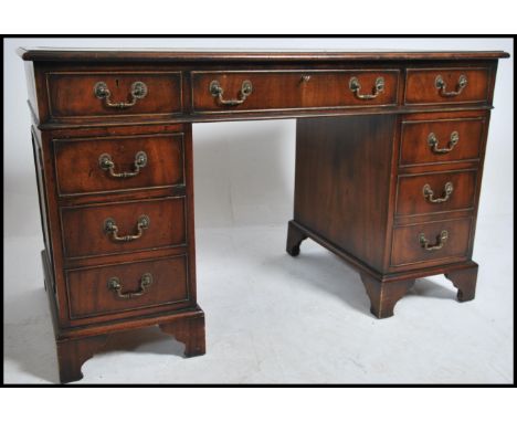 A Georgian style mahogany twin pedestal office writing desk raised on bracket feet with a series of drawers to each pedestal 