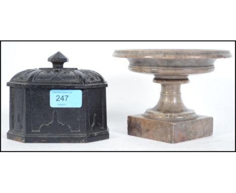 A polished stone urn with inclusive limpet fossils together with a cast iron ebonised tobacco jar having finial lid. The tall