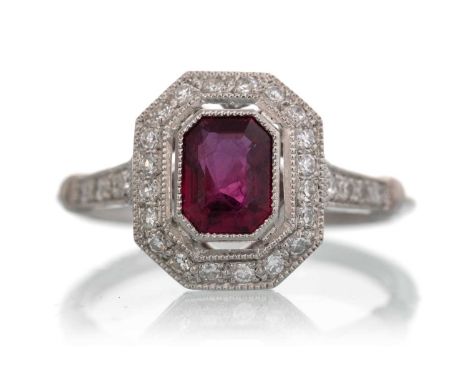 RUBY AND DIAMOND RING, set with a central octagonal step cut ruby, within a diamond halo, on diamond shoulders, in platinum, 