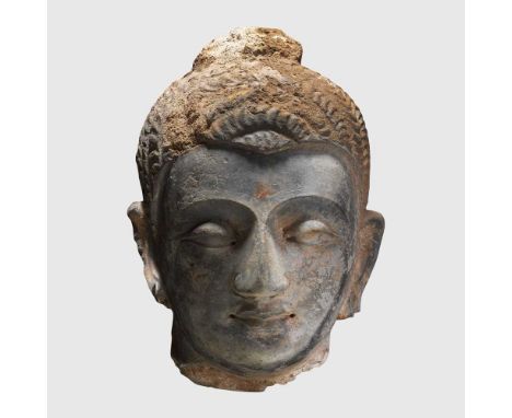 GANDHARAN HEAD OF BUDDHA GANDHARA, 4TH - 5TH CENTURY A.D. dark grey stucco, Buddha is depicted with a serene countenance, his