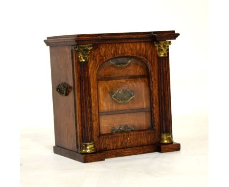 Early 20th Century oak table-top cabinet of inverted breakfront design with bevelled arch-glazed door between fluted Corinthi