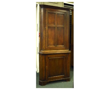 19th Century oak floor standing corner cupboard, the upper section with four-panelled door enclosing three shelves, the lower