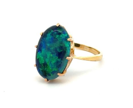 A solid black opal ring set in 18ct yellow gold, showing good blue and green play of colour. Opal approx 16mm x 10mm. Size N.