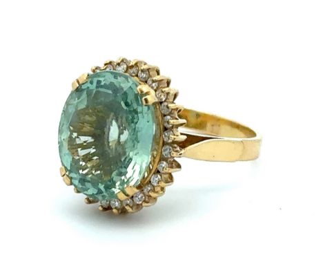 An oval cut aquamarine and diamond cluster ring set in 18ct gold. Aquamarine is approx 15mm x 12mm with a greenish blue hue. 