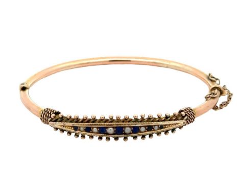 An unmarked 9ct gold hinged bangle. Bangle is set with blue stones and pearls and has rope twist and bead decoration. Small d