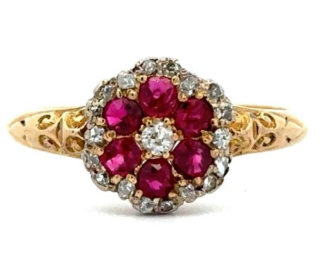 A ruby and diamond flower ring with scroll shoulders, stamped 18ct, size P. 3.02g. Please see the buyer's terms and condition