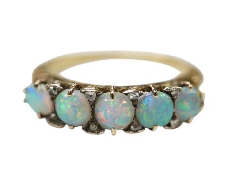 A yellow metal and graduated five stone cabochon white opal set half hoop ring, with diamond chip spacers, size Q/R, gross we