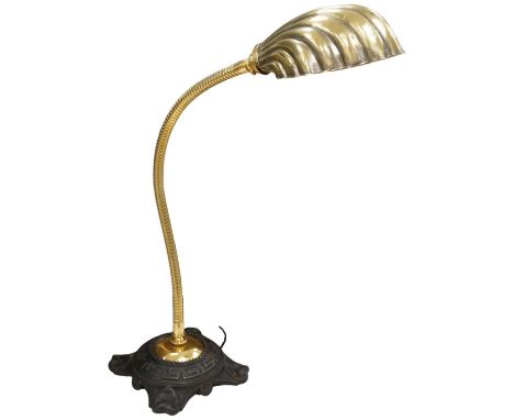 An English desk lamp wrought iron base with flexy brass arm and brass shell shape shade, early 20th century, wired, 55cm high