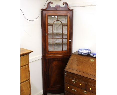 A 19th Century mahogany corner cupboard,&nbsp;the upper shelves enclosed by a single glazed panel door beneath a scroll arch 