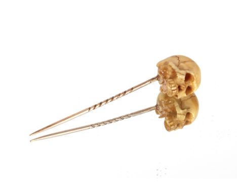 A bone and yellow metal stick pin, in the form of a skull